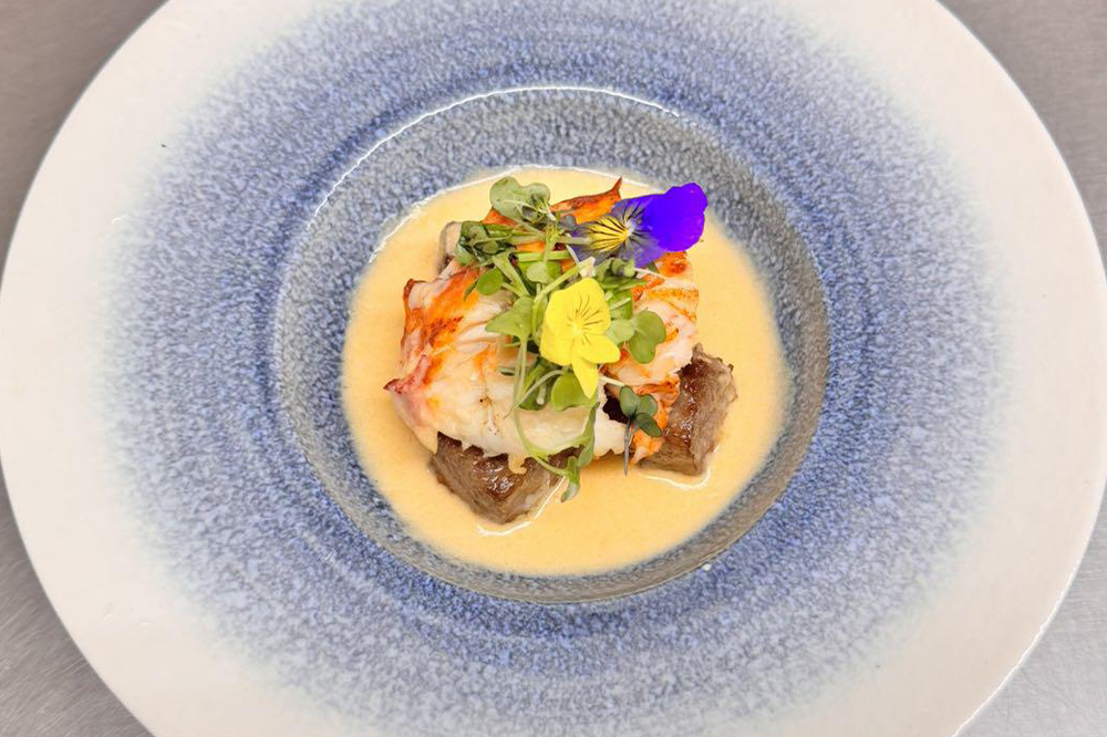 Plated lobster specialty dish with creamy sauce and microgreens